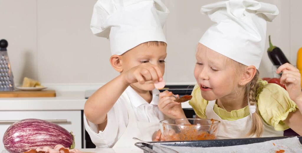 niños probando ingredientes para una pizza.