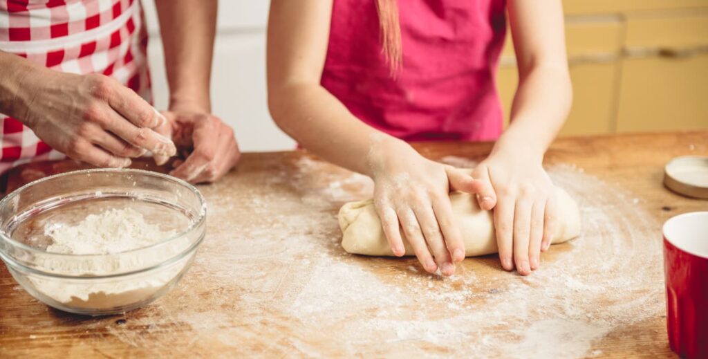 niña amasando base de pizza.