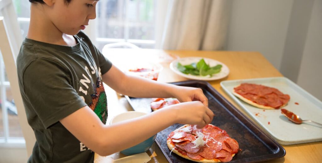 niño decorando una pizza.