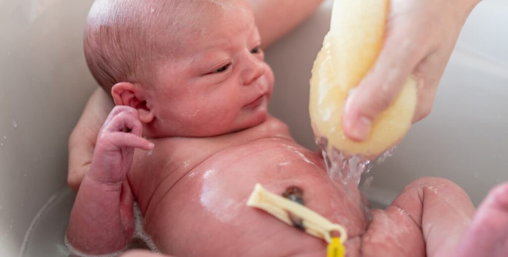 Baño del bebé con el cordón umbilical.